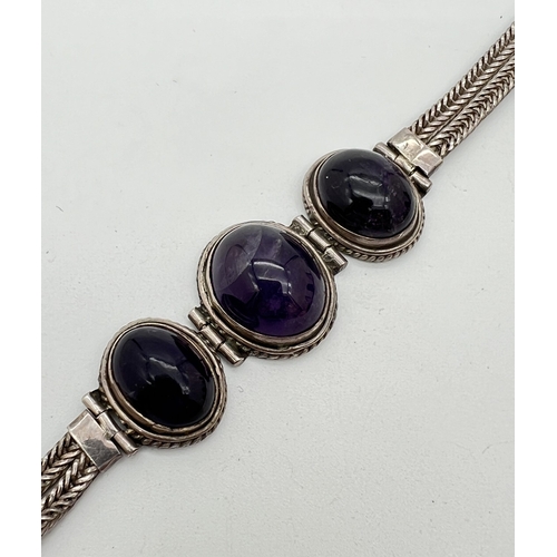 1036 - A 925 silver bracelet set with 3 large amethyst oval cabochons set in hinged rope design mounts. Wit... 