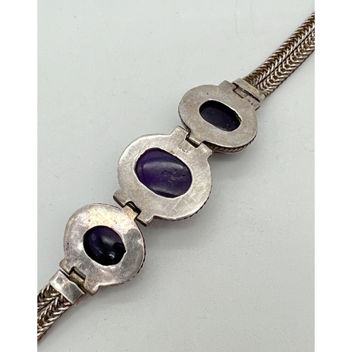 1036 - A 925 silver bracelet set with 3 large amethyst oval cabochons set in hinged rope design mounts. Wit... 