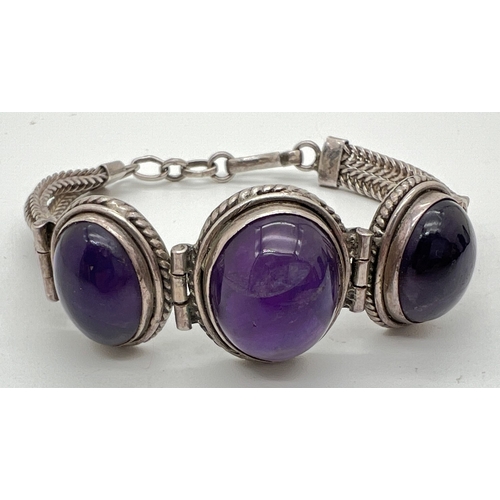 1036 - A 925 silver bracelet set with 3 large amethyst oval cabochons set in hinged rope design mounts. Wit... 