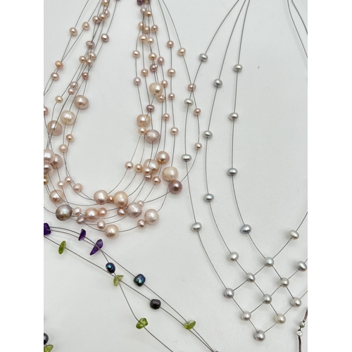 1049 - A faux suede box containing 8 assorted floating pearl style necklaces of varying styles and colours.... 