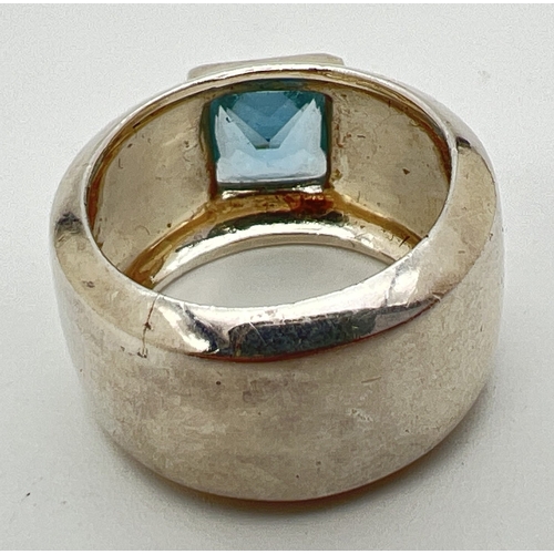 1015 - A modern design thick band ring with a bezel set square blue topaz stone. Ring size P. Silver marks ... 