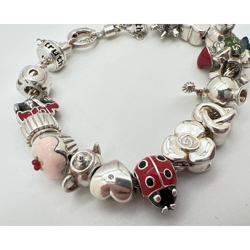 1016 - A 925 silver charm bracelet by Truth with 16 charms, some with enamel detail. Charms include double ... 