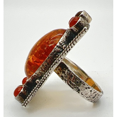 1026 - A large silver modern design amber set dress ring. Large central oval honey amber cabochon with 4 sm... 