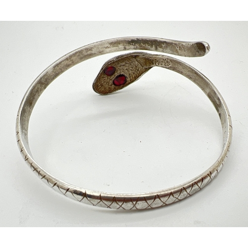 1038 - A vintage silver serpent bangle with criss cross decoration throughout and garnet set eyes. Marked S... 