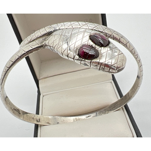 1038 - A vintage silver serpent bangle with criss cross decoration throughout and garnet set eyes. Marked S... 