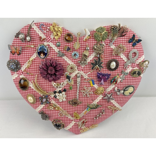 1061 - A padded heart shaped pin board containing approx. 60 assorted vintage brooches. To include enamelle... 