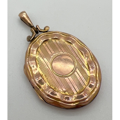 1066 - A vintage 9ct gold front and back oval shaped locket with scallop design edging. Engine turned decor... 