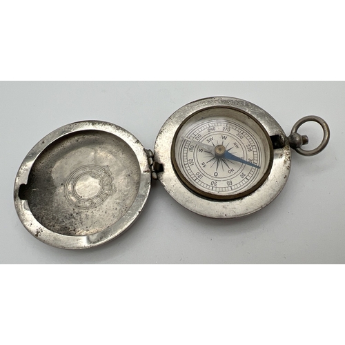 1310 - A vintage metal cased compass with wreath decoration to top of case. Approx. 4.5cm diameter.