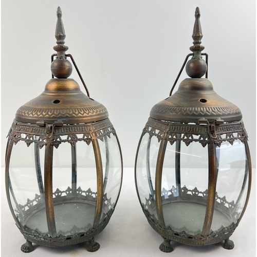 1324 - A pair of Eastern design bronzed effect metal and glass panelled lanterns with paw feet and hanging ... 