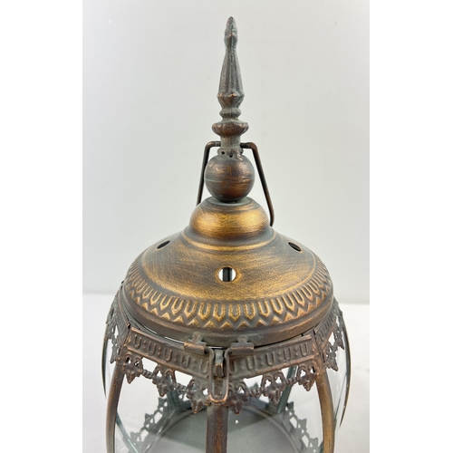 1324 - A pair of Eastern design bronzed effect metal and glass panelled lanterns with paw feet and hanging ... 