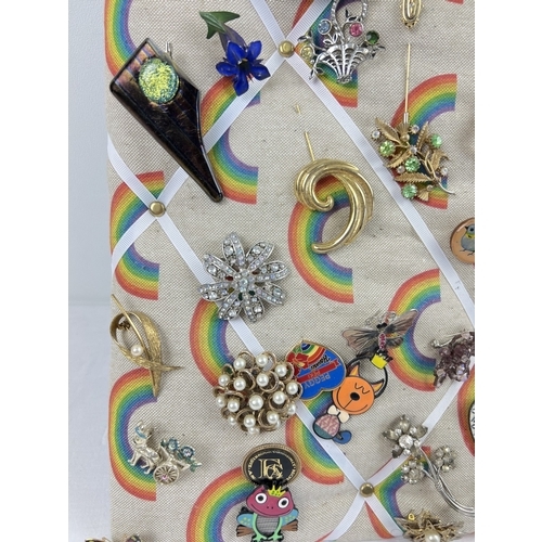 1060 - A padded pin board containing approx. 82 assorted vintage brooches. To include gold tone, stick pin,... 