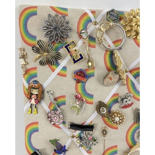 1060 - A padded pin board containing approx. 82 assorted vintage brooches. To include gold tone, stick pin,... 