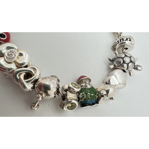 1016 - A 925 silver charm bracelet by Truth with 16 charms, some with enamel detail. Charms include double ... 