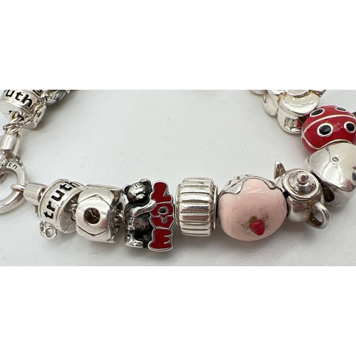 1016 - A 925 silver charm bracelet by Truth with 16 charms, some with enamel detail. Charms include double ... 