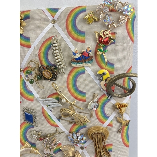 1060 - A padded pin board containing approx. 82 assorted vintage brooches. To include gold tone, stick pin,... 