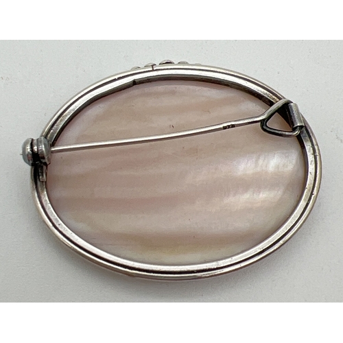 1101 - A vintage silver oval shaped brooch set with a piece of pale orange shell. With bead detail to top o... 