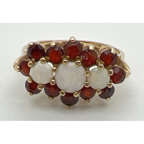 1104 - A 9ct gold opal and garnet ring set with 3 central round opals and 12 garnets ( 1 chipped). Fully ha... 