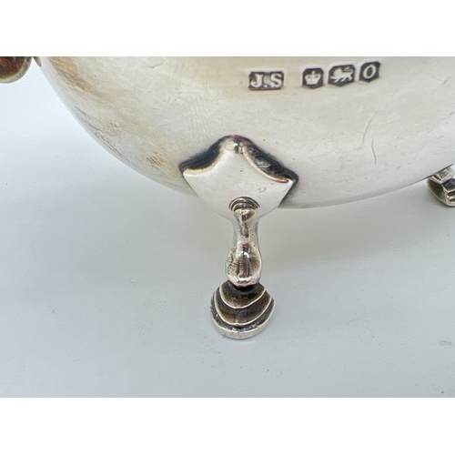 1205 - An Art Deco silver sauce boat with decorative scrolled handle and raised on tripod stepped design ho... 