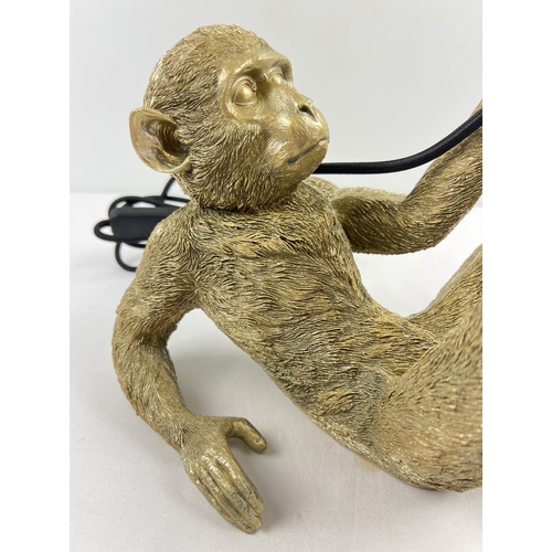 1326 - A modern gold coloured reclining monkey table lamp. Approx. 22cm tall x 31cm long.