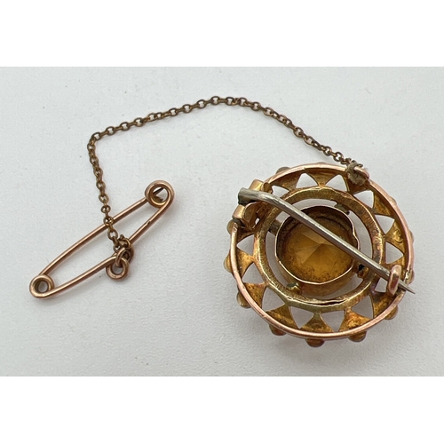 1001 - An antique 9ct gold circular brooch set with a central round cut citrine stone, surrounded by 14 see... 