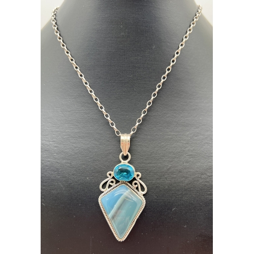 1005 - A modern design silver pendant set with a kite cut Botswana blue agate and an oval cut blue topaz. O... 