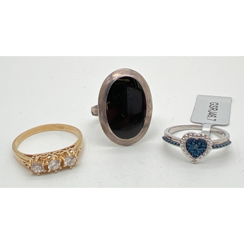 1062 - 3 silver stone set rings. An oval ring set with black onyx, a silver gilt 3 clear stone trilogy ring... 