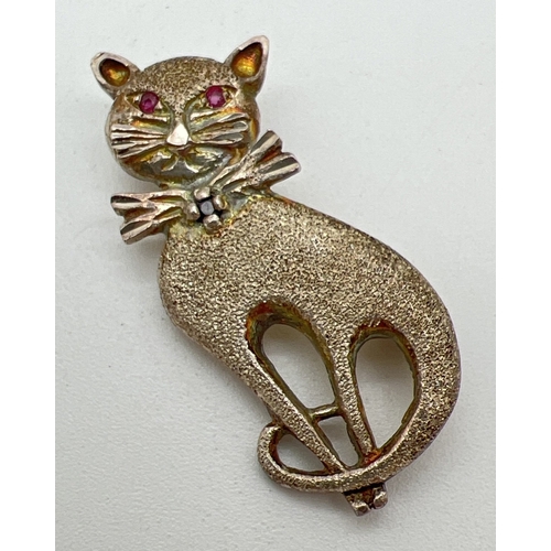 1065 - A vintage silver stone set cat brooch in brushed finish with bow tie detail. With small ruby set to ... 