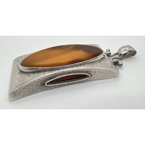 1006 - A large contemporary design silver pendant set with a large oval cut piece of amber. Hammered effect... 