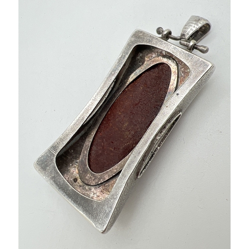 1006 - A large contemporary design silver pendant set with a large oval cut piece of amber. Hammered effect... 