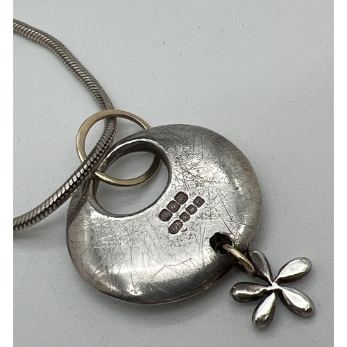 1079 - A modern design silver and 9ct gold circular shaped pendant with flower drop, by Scottish jewellery ... 