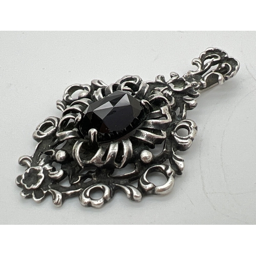 1082 - 2 pieces of silver jewellery. A large Gothic style floral detail pendant set with a central oval cut... 