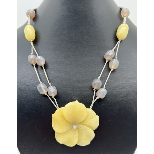 1100 - A yellow jade and grey stone beaded necklace with large carved flower shaped pendant and adjustable ... 