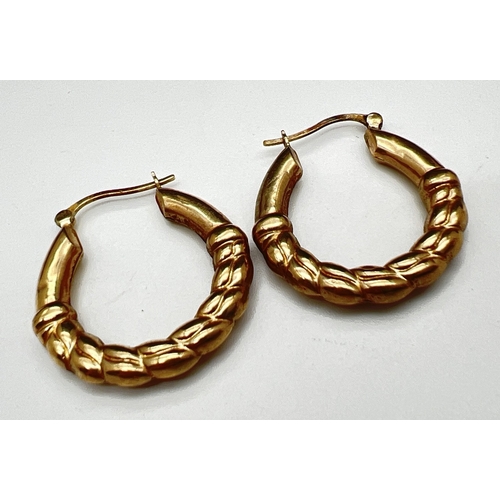 1114 - A pair of 9ct gold twisted hoop design Creole style earrings with hinged posts. Stamped 375. Approx.... 