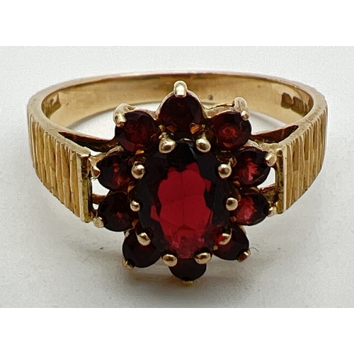 1118 - A vintage 9ct gold and garnet cluster ring with diamond cut detail to shoulders. Large central oval ... 