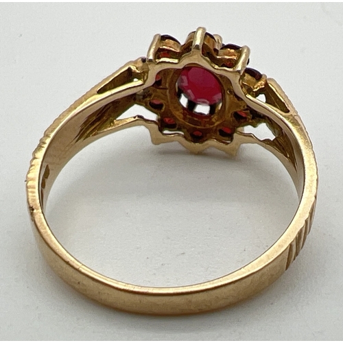 1118 - A vintage 9ct gold and garnet cluster ring with diamond cut detail to shoulders. Large central oval ... 