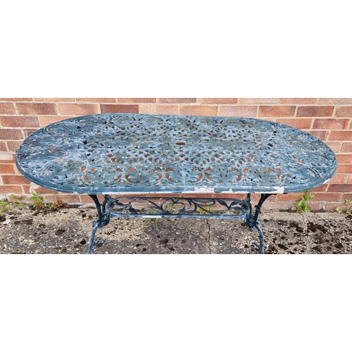 1433 - An oval shaped cast metal garden table, painted green, of scroll and foliate design. With central ho... 