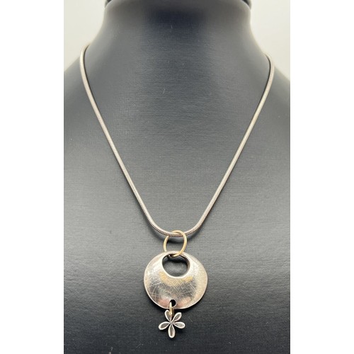 1079 - A modern design silver and 9ct gold circular shaped pendant with flower drop, by Scottish jewellery ... 