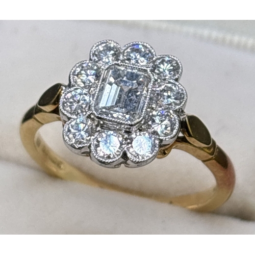 14 - A diamond cluster ring comprised of a central emerald cut diamond with a surround of 10 brilliant cu... 