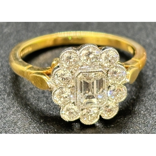 14 - A diamond cluster ring comprised of a central emerald cut diamond with a surround of 10 brilliant cu... 