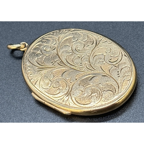 28 - A large 9ct gold oval shaped locket with engraved decoration of foliate design. Gold marks on back o... 