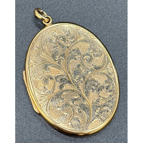 28 - A large 9ct gold oval shaped locket with engraved decoration of foliate design. Gold marks on back o... 