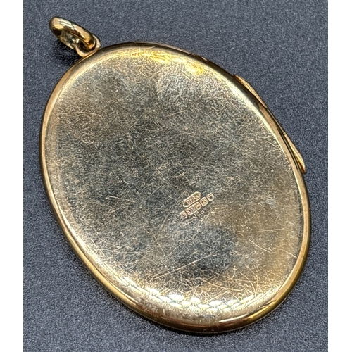 28 - A large 9ct gold oval shaped locket with engraved decoration of foliate design. Gold marks on back o... 