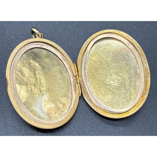 28 - A large 9ct gold oval shaped locket with engraved decoration of foliate design. Gold marks on back o... 