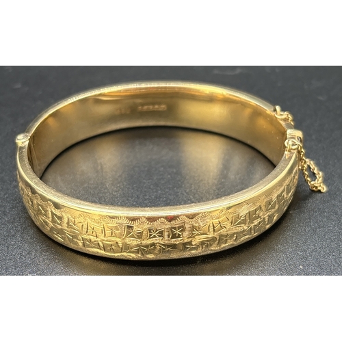 36 - A vintage 9ct gold half engraved hinged bangle with push clasp and safety chain. Engraved fluted edg... 