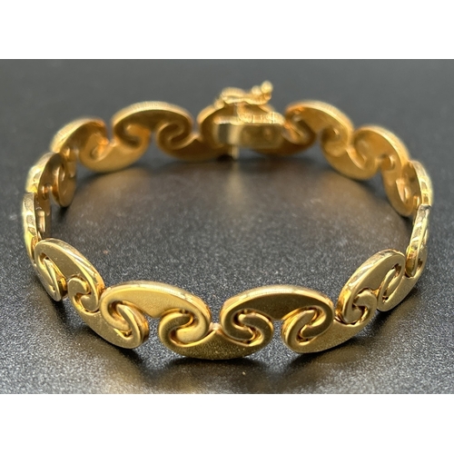 57 - A 9ct gold 7.5 inch interlocking curved link bracelet with push clasp and safety clip. Gold marks to... 