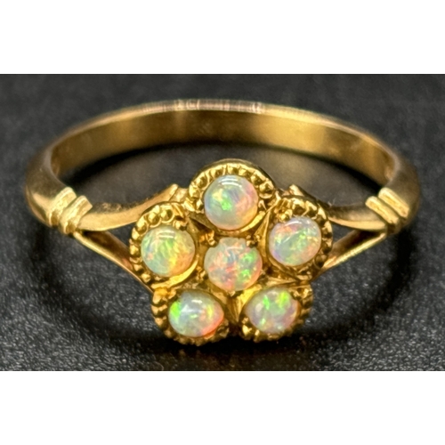 61 - An 18ct yellow gold opal set dress ring. 6 small round opals in a flower head design with split shou... 