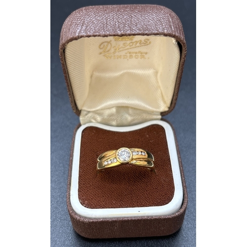 63 - A diamond dress ring set in 18ct yellow gold with crossover design band. Central round cut bezel set... 