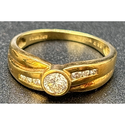 63 - A diamond dress ring set in 18ct yellow gold with crossover design band. Central round cut bezel set... 