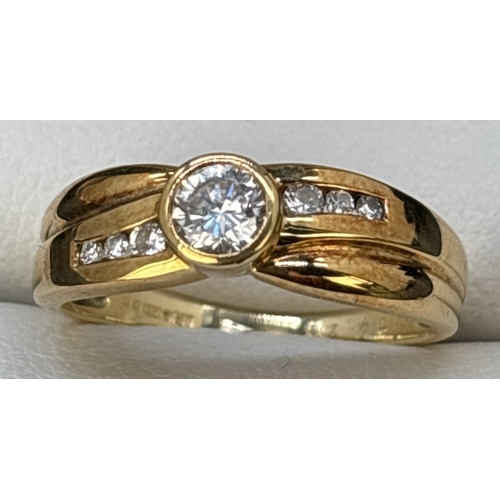 63 - A diamond dress ring set in 18ct yellow gold with crossover design band. Central round cut bezel set... 