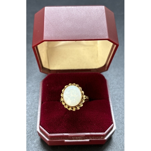 70 - A vintage 9ct gold large oval cut bezel set opal dress ring with twist design surround. Split should... 